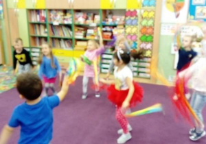 Dzieci tańczą na dywanie z chustkami w kolorach jesieni